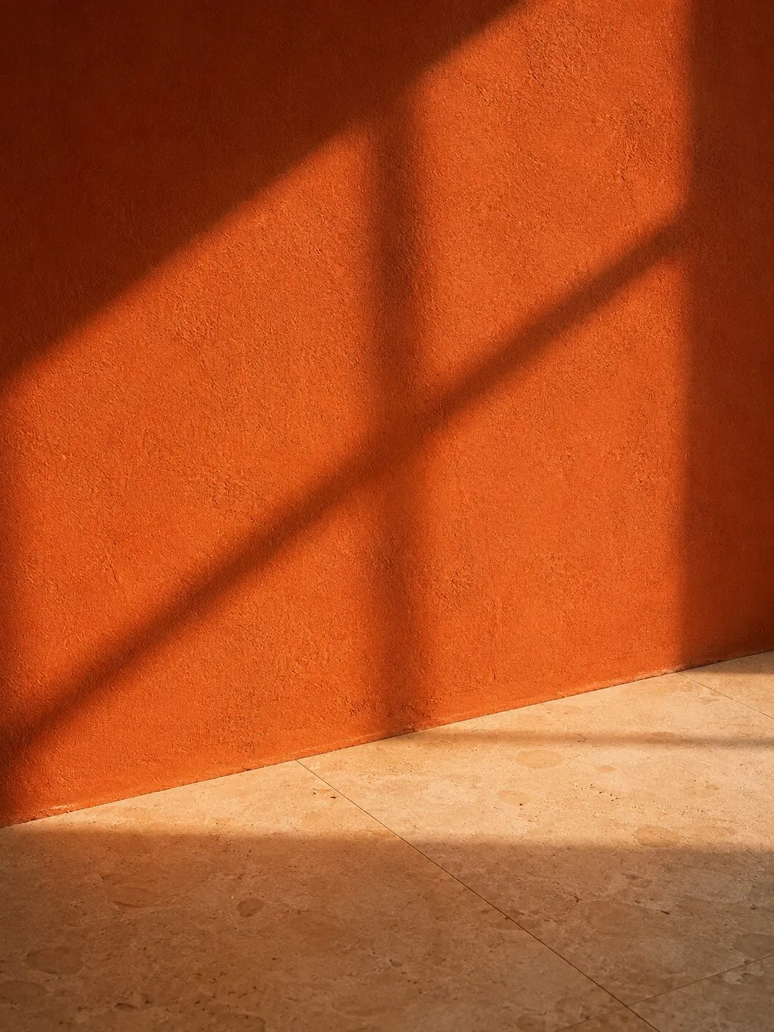 Window shadow across a terracotta plaster wall